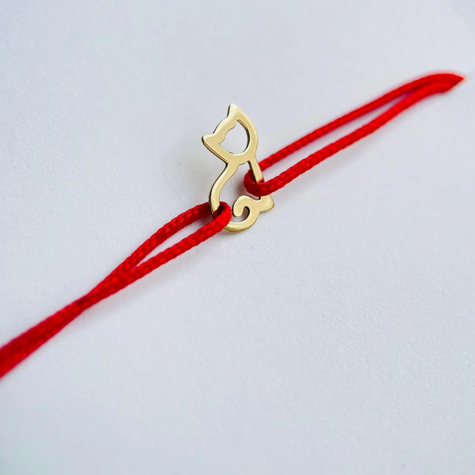 Brățară din aur cu șnur roșu și pandantiv în formă de pisică